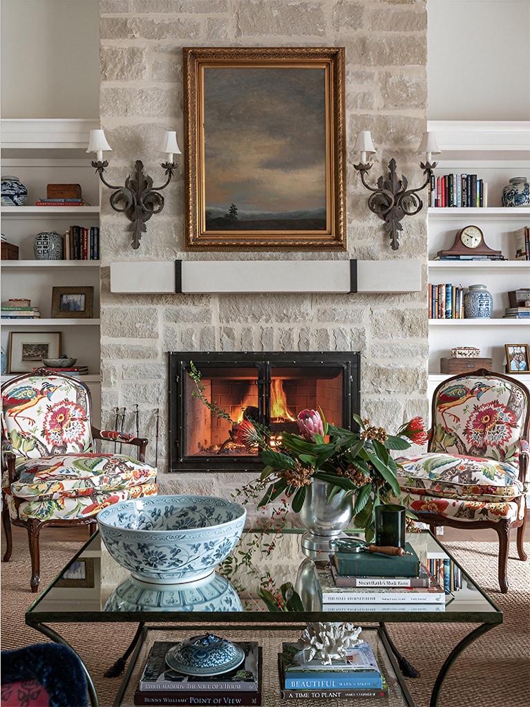 Living room with a lit fireplace framed by patterned armchairs